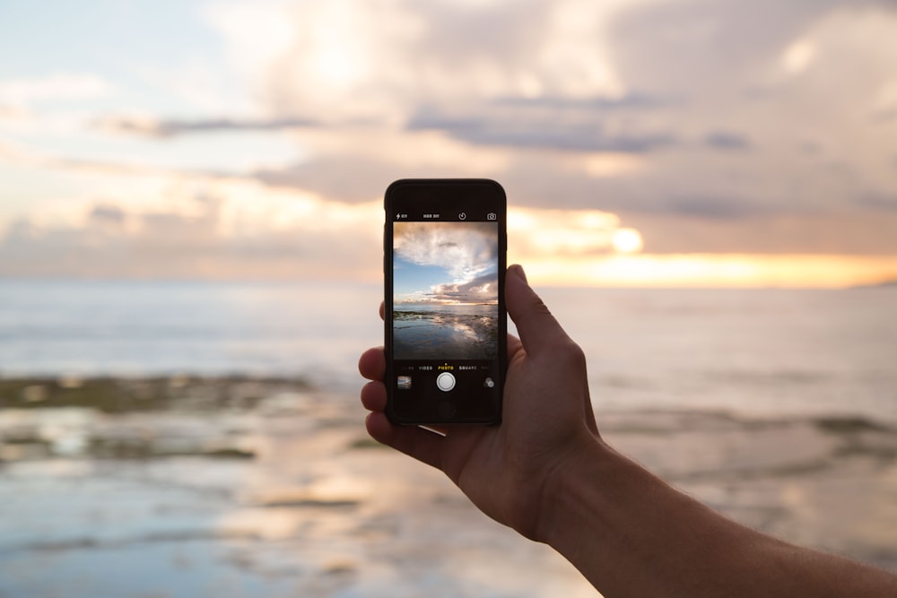 Persona che tiene lo smartphone che mostra l'oceano