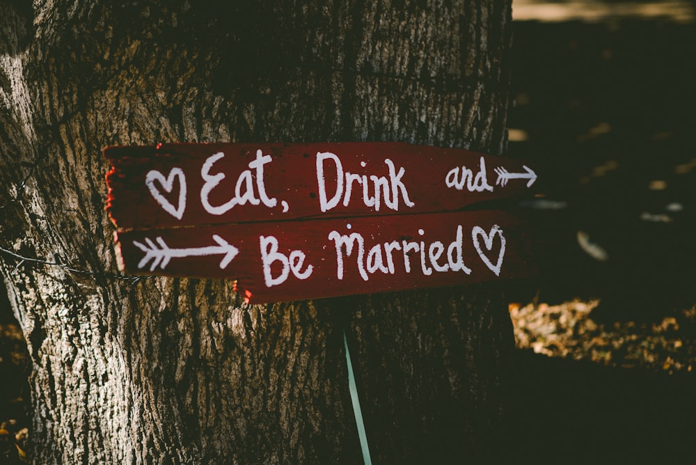 Rot und Weiß essen, trinken und heiraten Beschilderung in der Nähe von braunem Baum