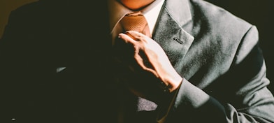 A man in a black suit loosening his tie