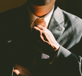 A man in a black suit loosening his tie