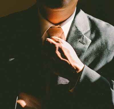 A man in a black suit loosening his tie