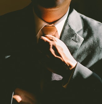 A man in a black suit loosening his tie