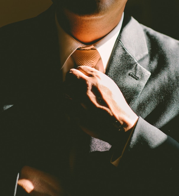 A man in a black suit loosening his tie