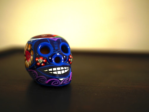 A colorful handcrafted skull figurine with intricate carnival-themed decorations.