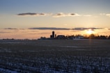 Sunset over the farmland showing rows of harvested fields and equipment.