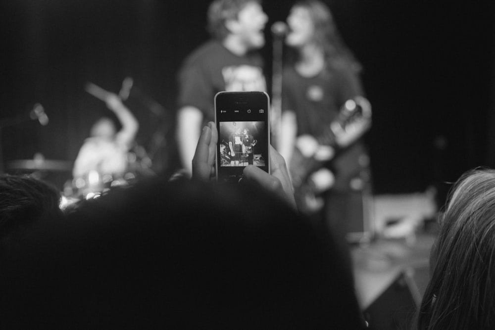 grayscale photo of woman taking photo of people