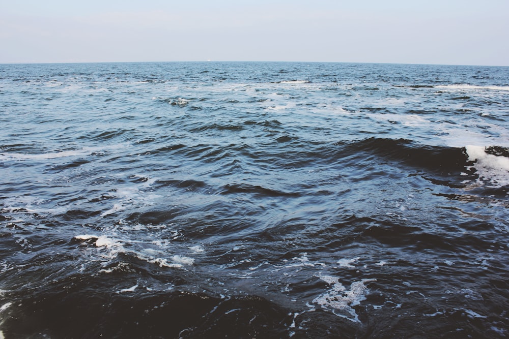 calmo specchio d'acqua sotto il cielo blu durante il giorno