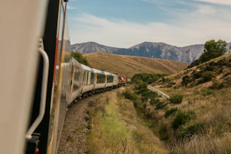 A scenic international train winding through picturesque landscapes under a clear sky.