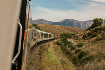 A scenic international train winding through picturesque landscapes under a clear sky.