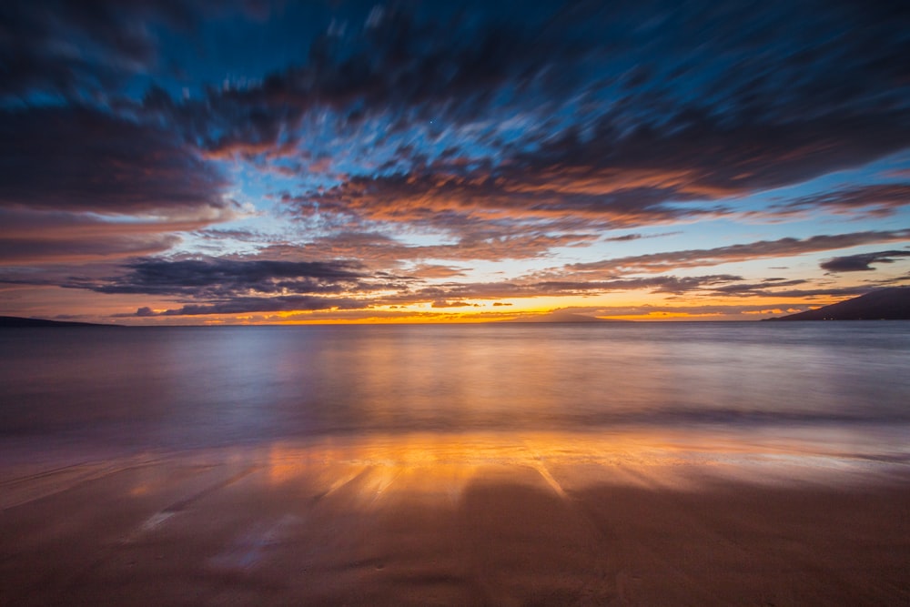 Foto timelapse di spiaggia calma sotto cielo blu e nuvole bianche