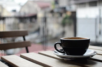 A cozy coffee cup resting on a wooden table with the Dallas skyline softly blurred in the background.