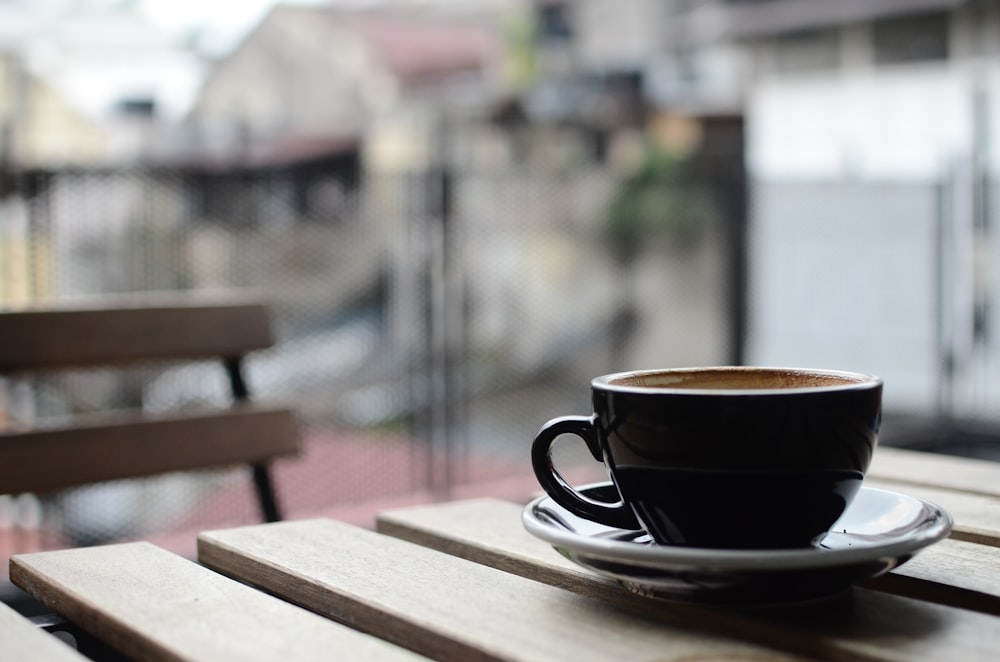 Photographie sélective de la tasse et de l’assiette à thé en céramique noire sur une table en bois brun pendant la journée