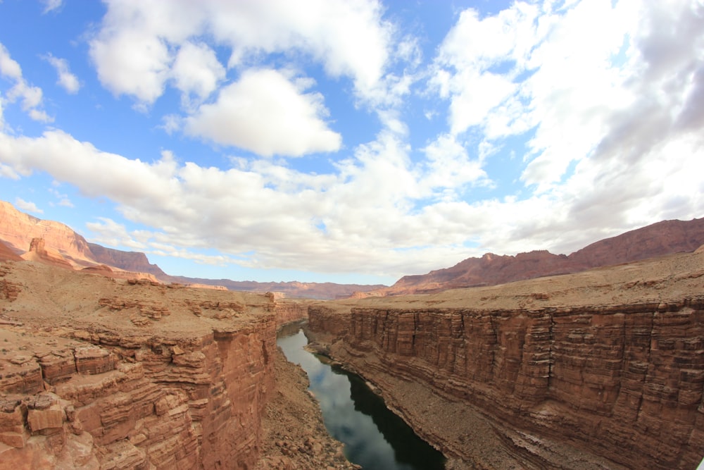 brown rocky mountain beside river under blue sky during daytime