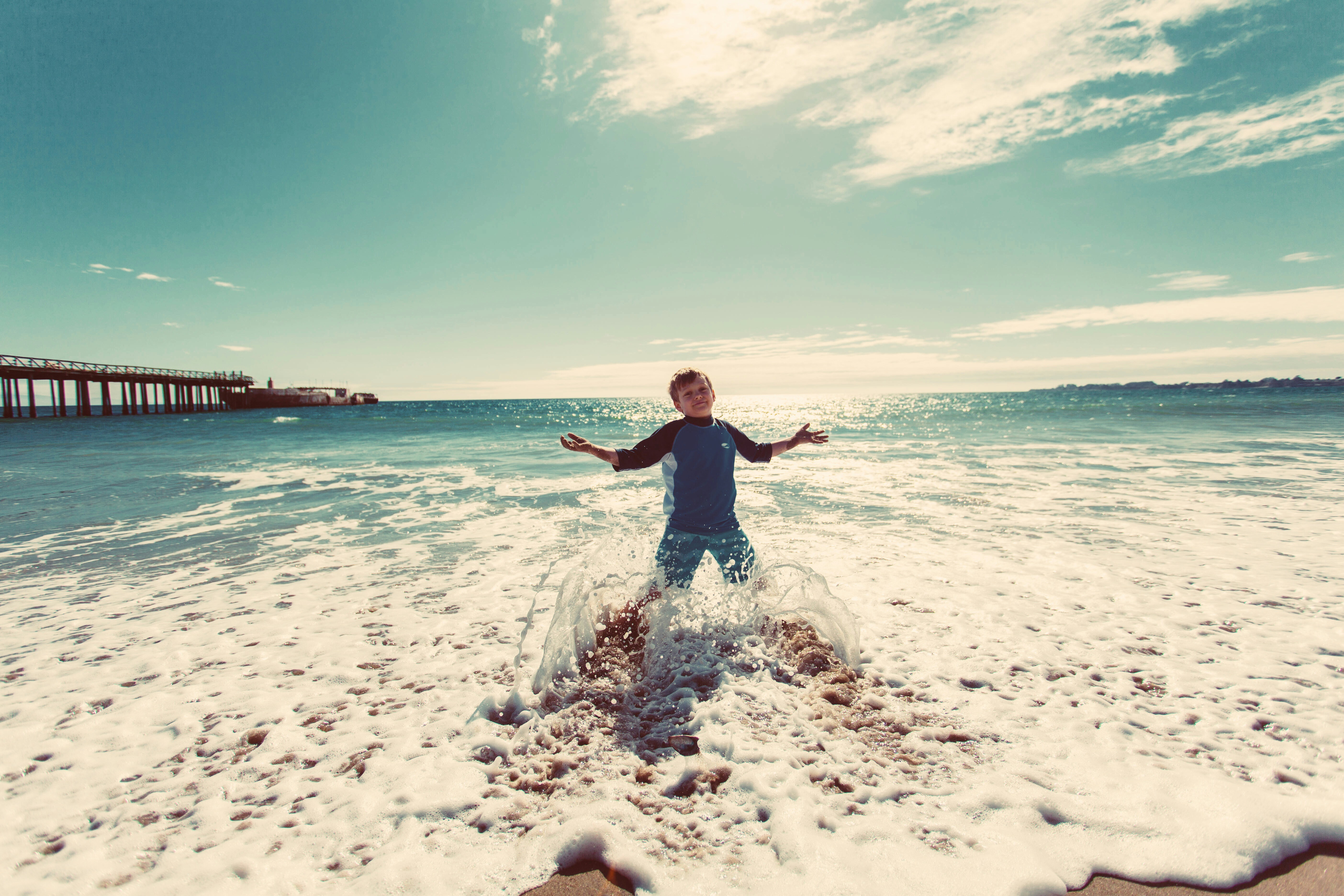 boy playing on shore under blue sky during daytime