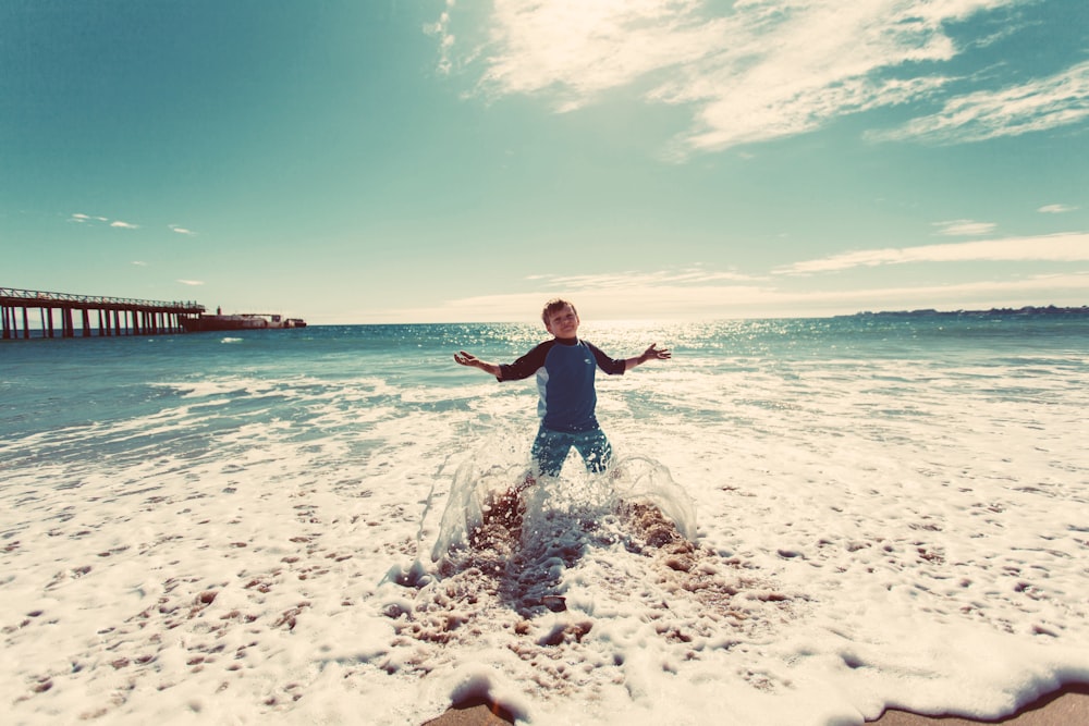 boy playing on shore under blue sky during daytime