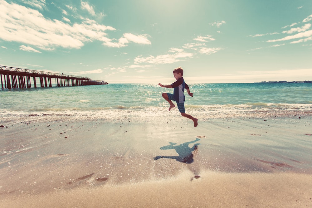boy in wetsuit jumping on shore