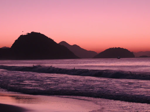 A serene beach sunset with gentle waves and a golden sky reflecting the colors of Kahuakai Viajes' brand.