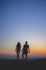 man and woman holding hands in silhouette photography