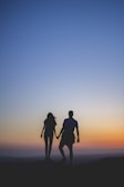man and woman holding hands in silhouette photography