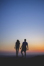 man and woman holding hands in silhouette photography