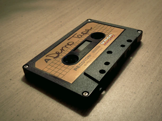 Close-up of a vintage cassette tape with handwritten labels on a wooden table.