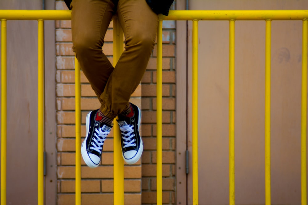 person sitting on rail fence