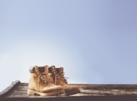 Close-up of worn hiking boots resting on a weathered wooden bench.
