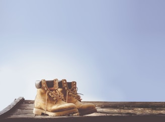 Close-up of worn hiking boots resting on a weathered wooden bench.