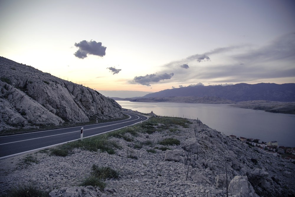 gray concrete road near body of water during daytime