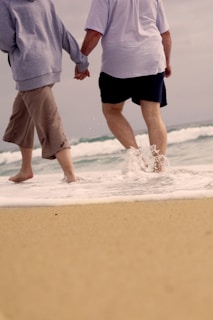 A romantic couple strolling hand in hand along a picturesque shoreline.