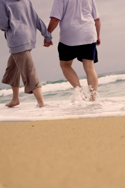 A romantic couple strolling hand in hand along a picturesque shoreline.