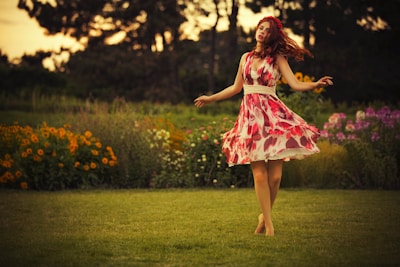 A joyful little girl twirling in a soft pastel dress under a sunlit garden arch.