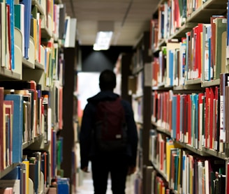 man with backpack beside a books