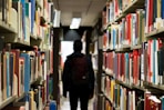 man with backpack beside a books