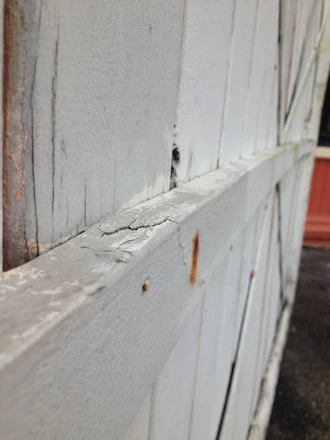 Close-up of a weathered wooden fence with a sagging gate and leaning posts.