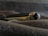 A luxury pen with a glossy black and gold finish, lying on a textured surface. The pen features intricate details, including a shiny cap with a distinctive emblem at the end.