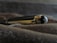A luxury pen with a glossy black and gold finish, lying on a textured surface. The pen features intricate details, including a shiny cap with a distinctive emblem at the end.