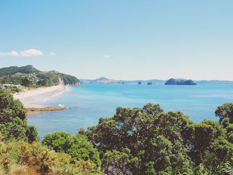 A scenic view of Lombok's pristine beach with clear blue waters and lush green hills in the background.