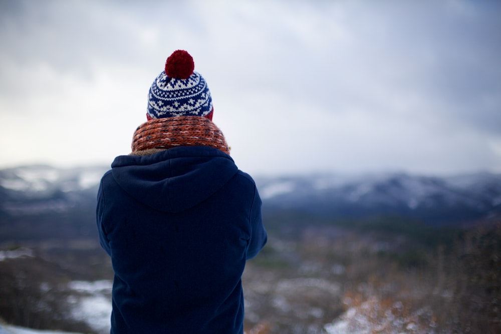 person wearing blue hoodie facing mountains