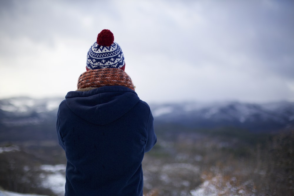 person wearing blue hoodie facing mountains