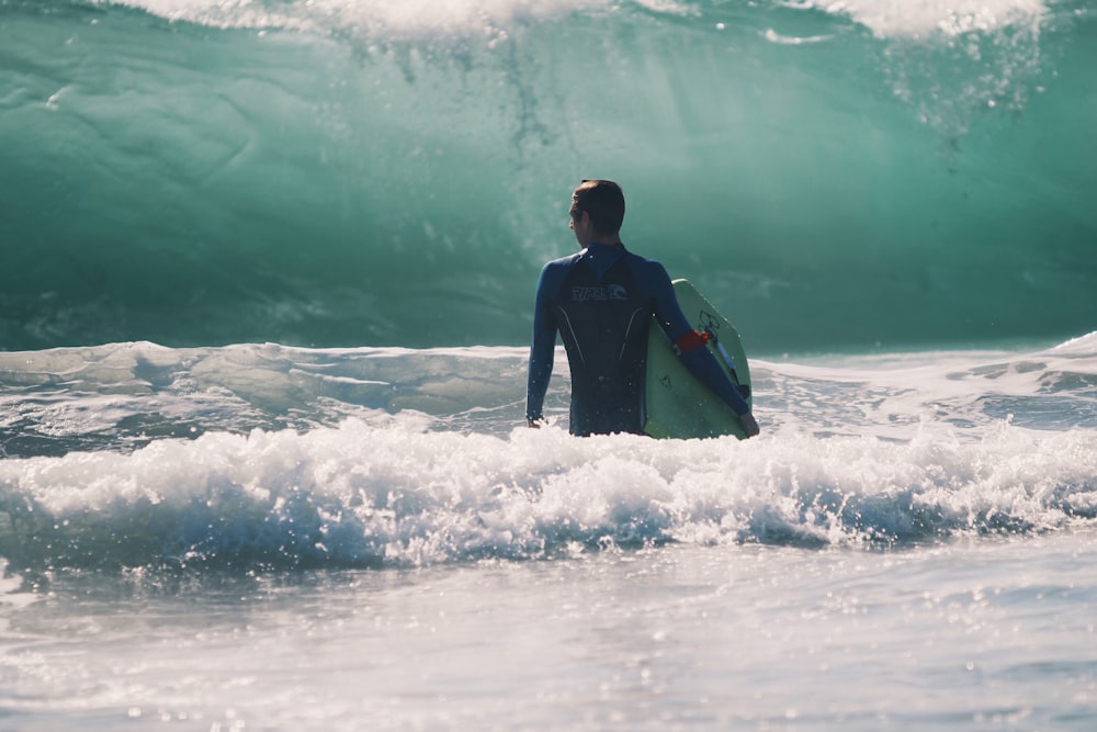 man standing in body of water holding surfboard