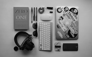 black corded headphones, silver MacBook, Apple wireless keyboard, and Apple Magic Mouse