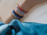 A stack of colorful beaded bracelets worn on a woman's wrist in natural sunlight.