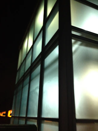 An architectural rendering of a modern glass building illuminated with subtle gradient lighting, emphasizing clean lines and depth.