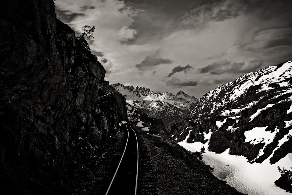 gray train rail beside snow covered mountain