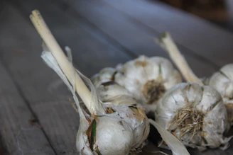 Close-up of fresh garlic bulbs stacked neatly in a rustic wooden crate, bathed in natural light.