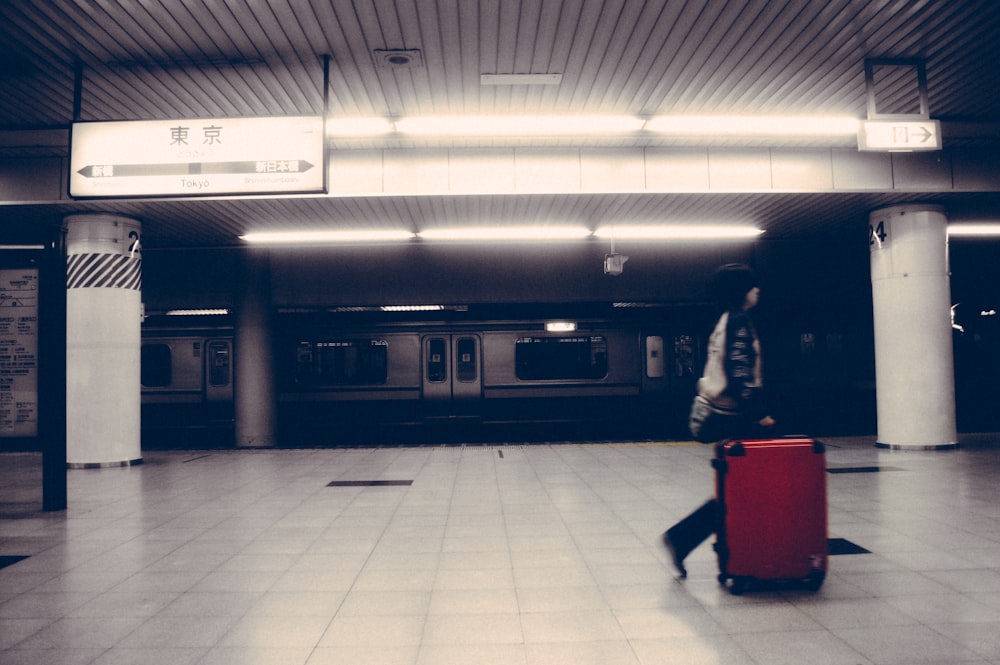 persona che cammina con borsa bagagli vicino al treno all'interno dell'edificio