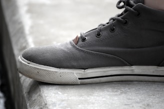 Close-up of edgy sneakers with unique textures and colors, resting on a gritty concrete floor.
