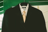 A sleek navy suit jacket hanging against a minimalist wall, perfectly tailored.