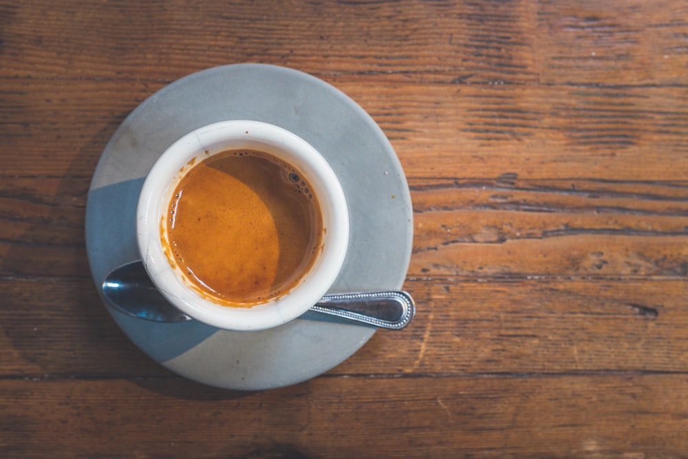 filled white cup on top of gray saucer